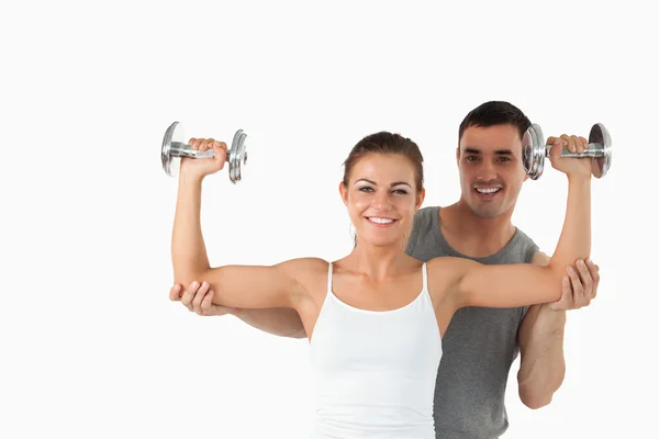 Young man helping a smiling woman to work out — Stock Photo, Image