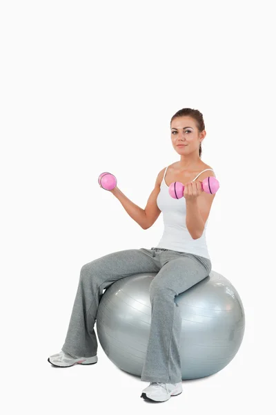 Retrato de una mujer haciendo ejercicio con pesas y una pelota —  Fotos de Stock