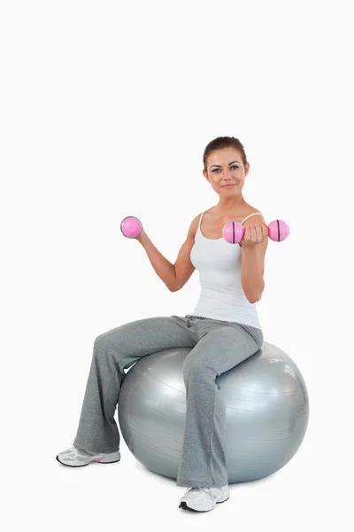 Retrato de una mujer en forma haciendo ejercicio con pesas y una pelota —  Fotos de Stock