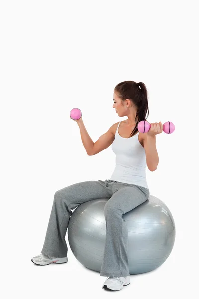 Retrato de una joven haciendo ejercicio con pesas y una pelota —  Fotos de Stock