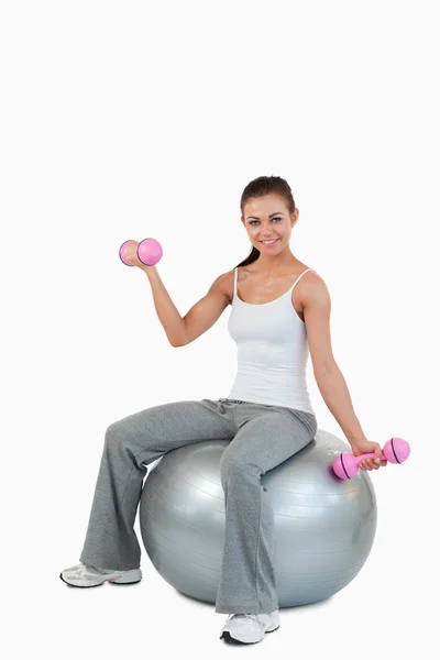 Retrato de una mujer sonriente haciendo ejercicio con pesas y un bal —  Fotos de Stock