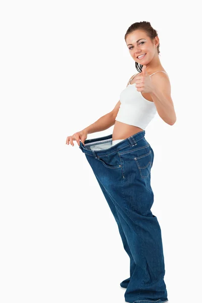 Retrato de una mujer usando pantalones demasiado grandes con el pulgar hacia arriba —  Fotos de Stock