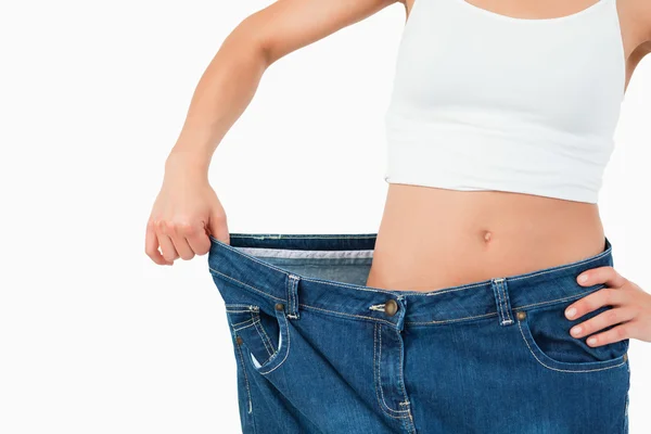 Fit woman wearing too large jeans — Stock Photo, Image