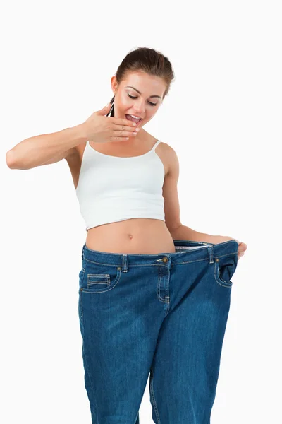 Retrato de una mujer sorprendida usando jeans demasiado grandes — Foto de Stock