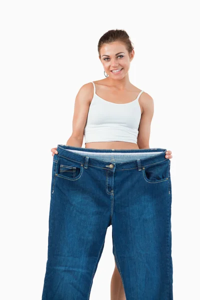 Portrait of a woman showing large jeans — Stock Photo, Image