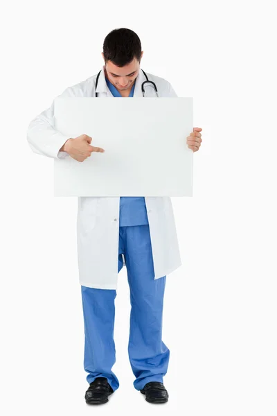 Portrait of a young doctor pointing at a blank panel — Stock Photo, Image