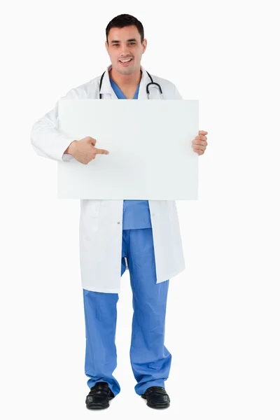Retrato de um belo médico apontando para um painel em branco — Fotografia de Stock