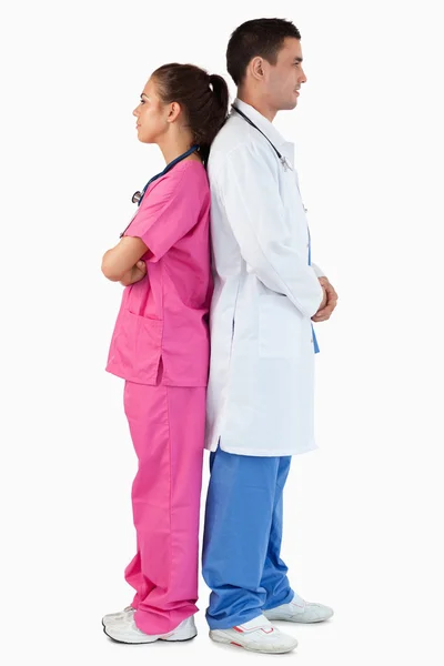 Porträtt av en läkare och en sjuksköterska som poserar rygg mot rygg — Stockfoto