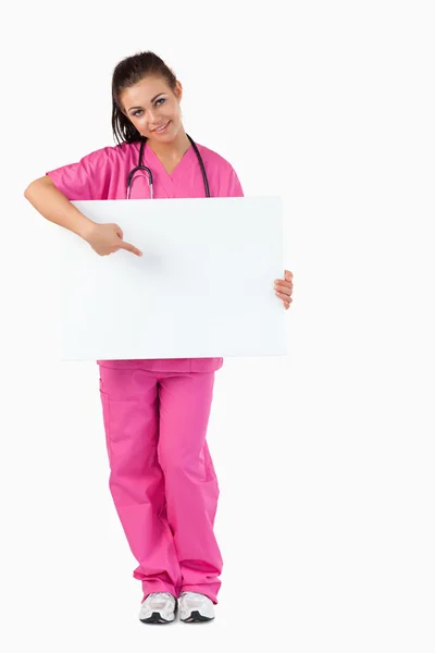 Portrait of a brunette doctor pointing at a blank panel — Stock Photo, Image