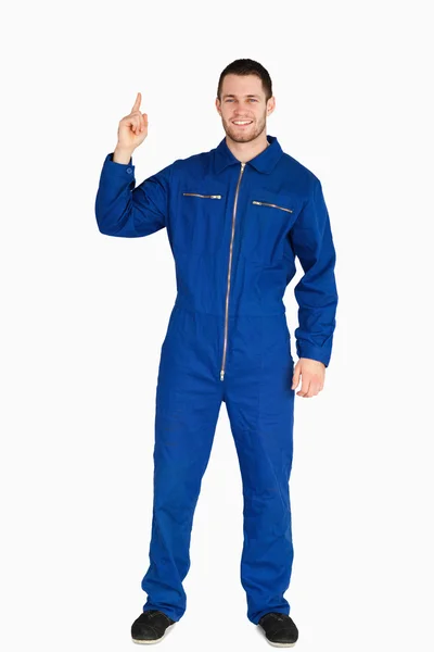 Smiling young mechanic in boiler suit pointing up — Stock Photo, Image