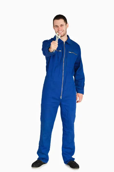 Smiling young mechanic in boiler suit presenting his wrench — Stock Photo, Image