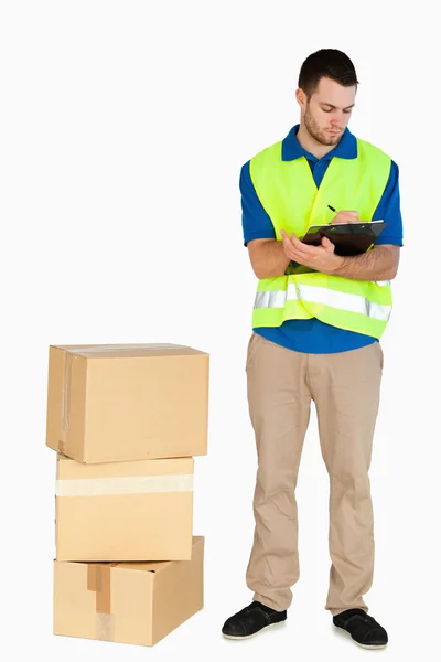 Young delivery man filling in delivery note — Stock Photo, Image
