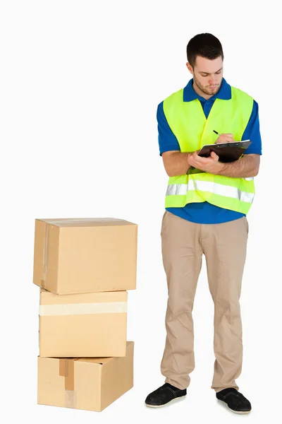 Young delivery man completing delivery note — Stock Photo, Image