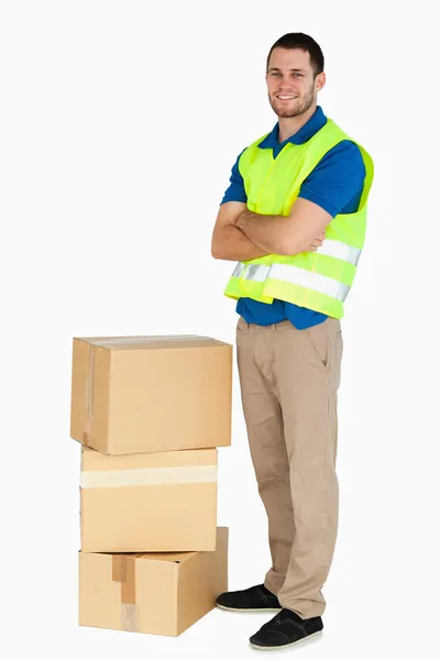 Smiling young delivery man with arms folded — Stock Photo, Image