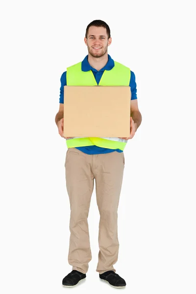 Sorrindo jovem entregador carregando uma parcela — Fotografia de Stock
