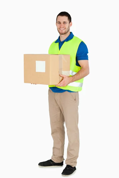 Sorridente giovane uomo di consegna in possesso di un pacco — Foto Stock