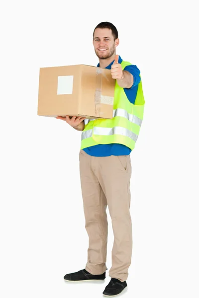 Sorridente giovane uomo di consegna dando l'approvazione, mentre in possesso di un pacchetto — Foto Stock