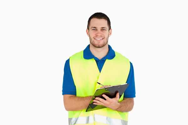 Smiling young delivery man completing delivery note — Stock Photo, Image