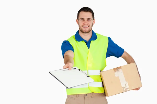 Smiling young delivery man with parcel asking for signature — Stock Photo, Image