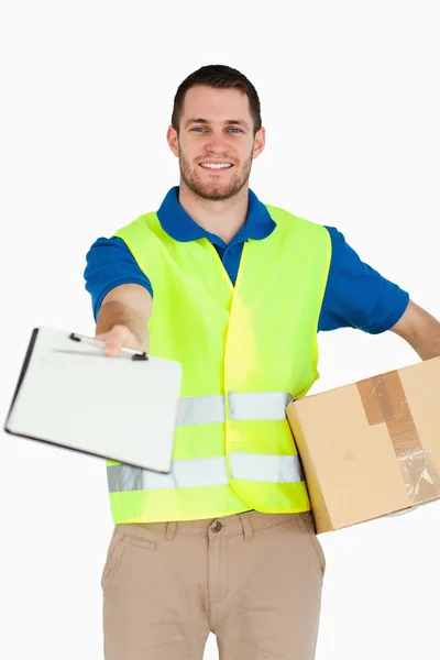 Sorrindo jovem entregador com pacote pedindo assinatura — Fotografia de Stock