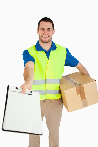 Smiling young delivery man handing over delivery note for signat — Stock Photo, Image
