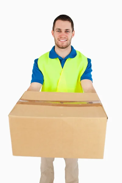 Smiling young delivery man handing over parcel — Stock Photo, Image