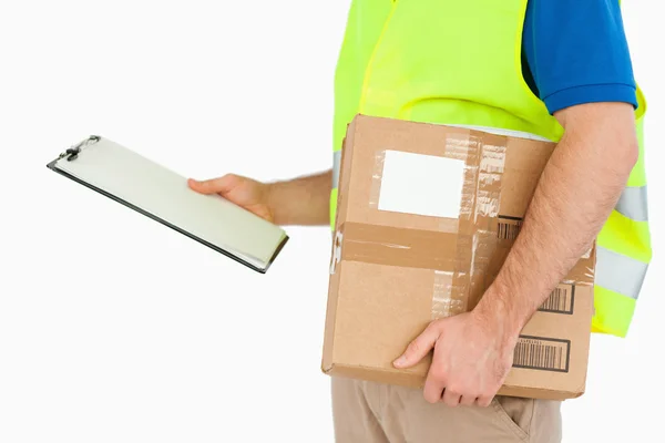 Side view of young delivery man with delivery note and parcel — Stock Photo, Image