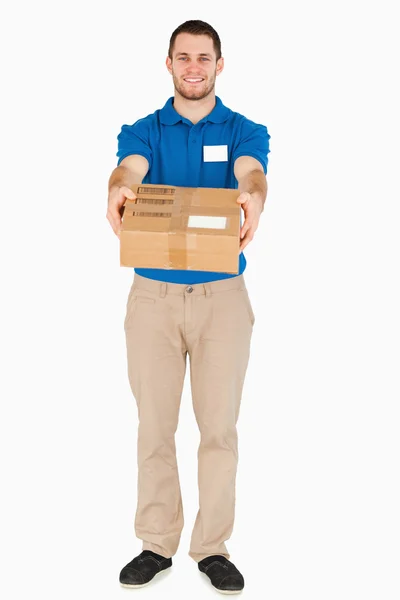 Smiling young salesman handing over parcel — Stock Photo, Image