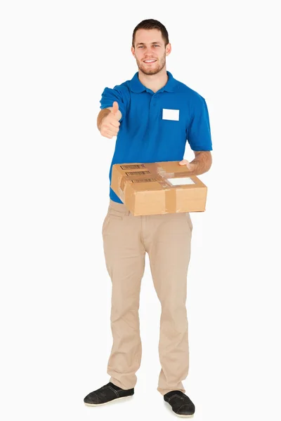 Sonriente joven vendedor con paquete dando pulgar hacia arriba —  Fotos de Stock