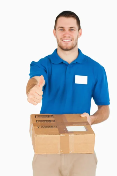 Paquete entregado por sonriente joven vendedor dando pulgar hacia arriba — Foto de Stock