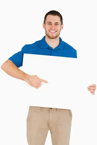 Uśmiechający się młody sprzedawca, wskazując na banner w ręce — Zdjęcie stockowe