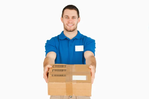 Sorridente giovane assistente di vendita consegna pacco — Foto Stock