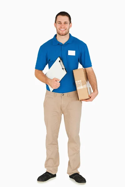 Smiling young salesman with clipboard and parcel — Stock Photo, Image