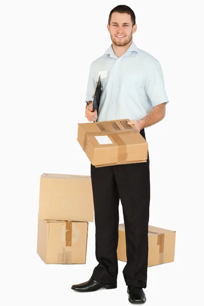 Sorrindo jovem funcionário post com prancheta entregando parcela — Fotografia de Stock