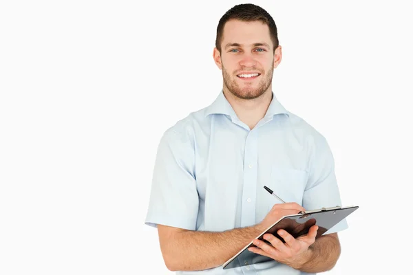 Sorrindo jovem funcionário do correio tomar notas na área de transferência — Fotografia de Stock