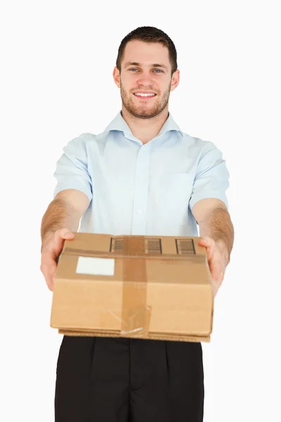 Sorridente giovane impiegato postale consegna pacco — Foto Stock