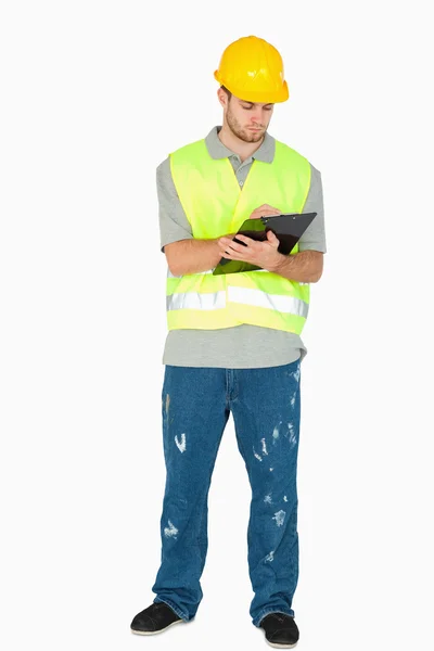 Jovem trabalhador da construção tomando notas em sua área de transferência — Fotografia de Stock