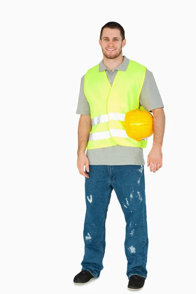 Sonriente joven obrero de la construcción llevando su casco debajo de su —  Fotos de Stock