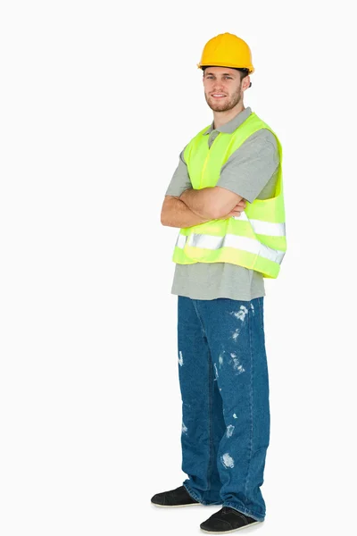 Vista lateral de sorrir jovem trabalhador da construção com os braços dobrados — Fotografia de Stock