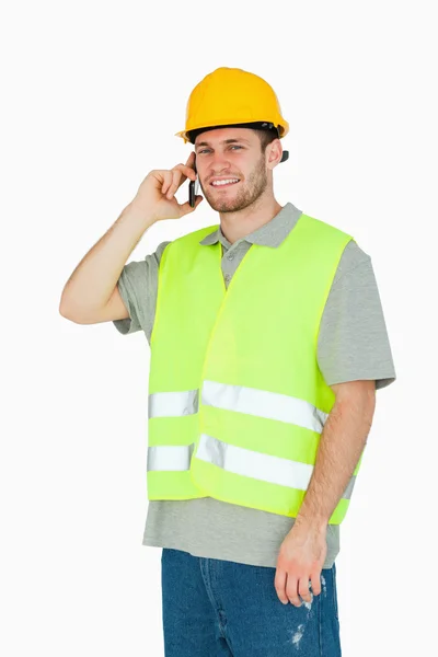Sorrindo jovem trabalhador da construção no telefone móvel — Fotografia de Stock