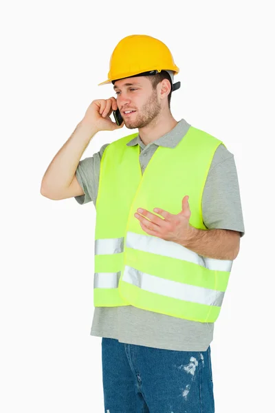 Молодой строитель обсуждает по мобильному телефону — стоковое фото