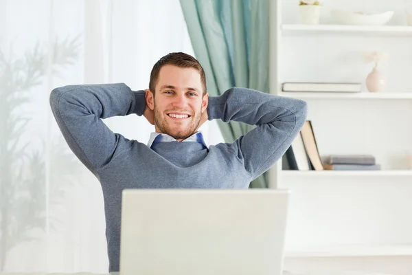 Smiling businessman leaning back in his homeoffice — Stock Photo, Image