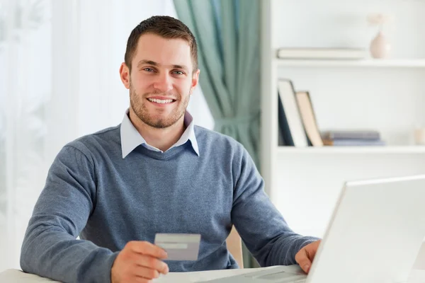 Smiling male with credit card at his laptop — Stock Photo, Image