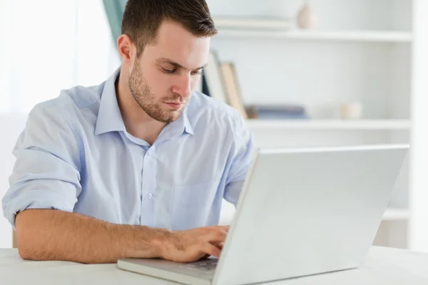 Empresário com mangas arregaçadas em seu escritório em seu laptop — Fotografia de Stock