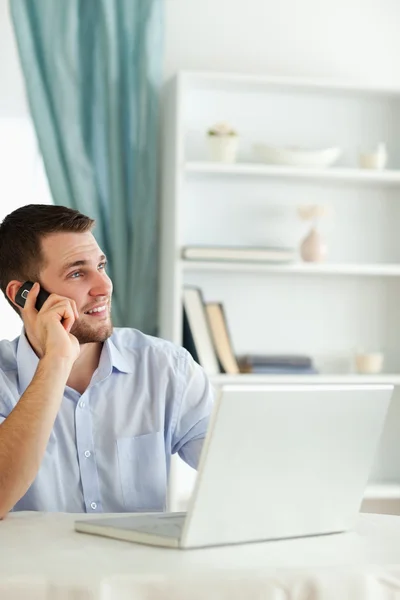 Uśmiechający się biznesmen w swoim homeoffice za pomocą jego telefon — Zdjęcie stockowe