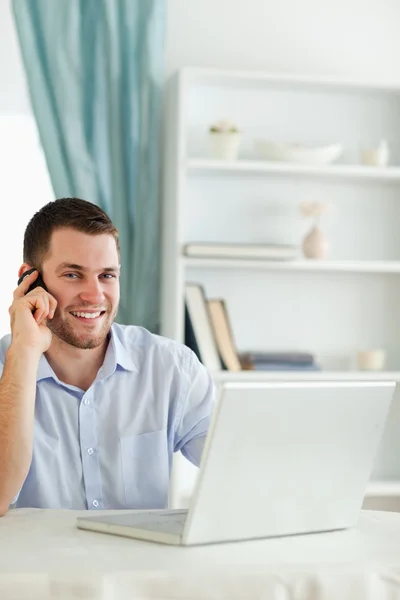 Usmívající se podnikatel v jeho homeoffice na telefonu — Stock fotografie