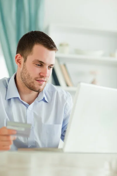 Empresário com cartão de crédito e laptop em seu escritório — Fotografia de Stock
