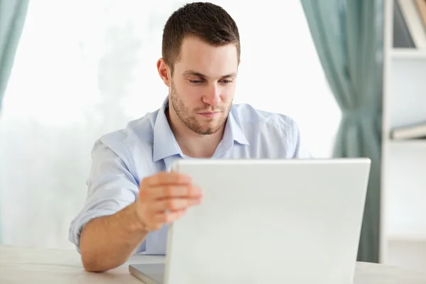 Zakenman achter zijn tafel zittend op zijn laptop — Stockfoto