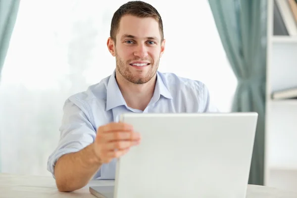 Lachende zakenman achter een tafel zittend op zijn laptop — Stockfoto