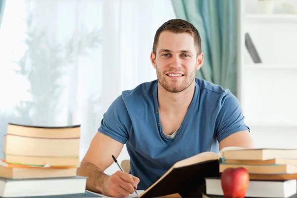 Lächelnder Student bei der Arbeit an seinem Buchbericht — Stockfoto